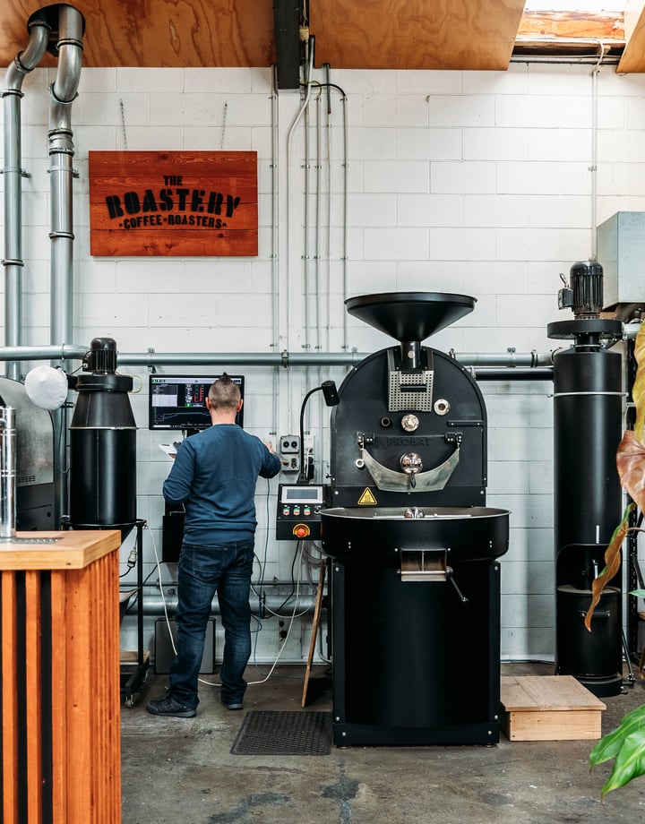 Man standing at coffee bean roaster.