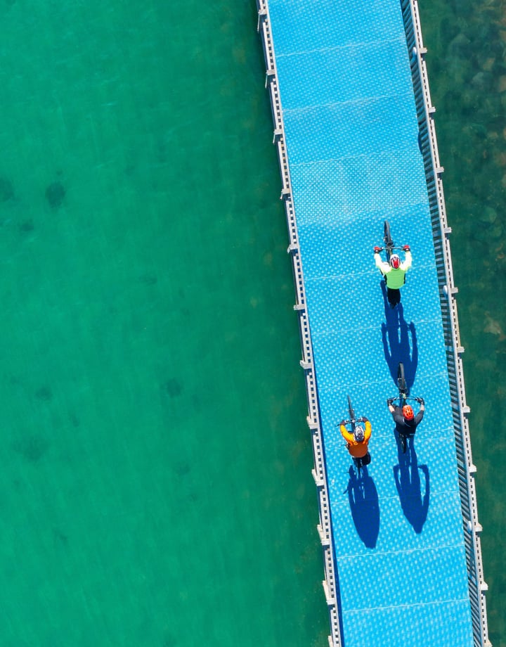 Three people biking on a bike trail over water.