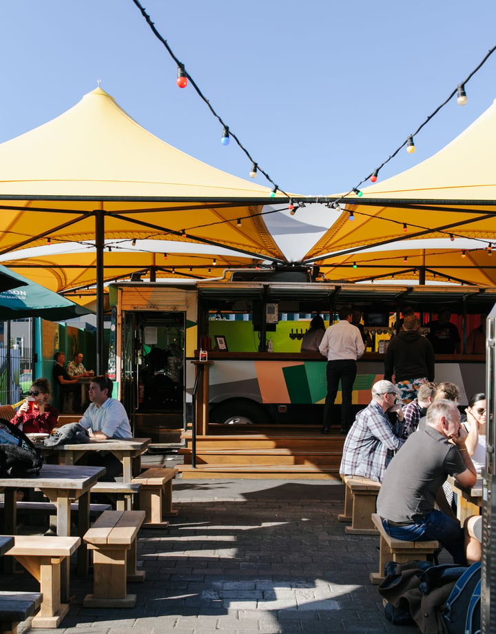 Lots of people sitting around tables at Smash Palace Christchurch on a sunny day.