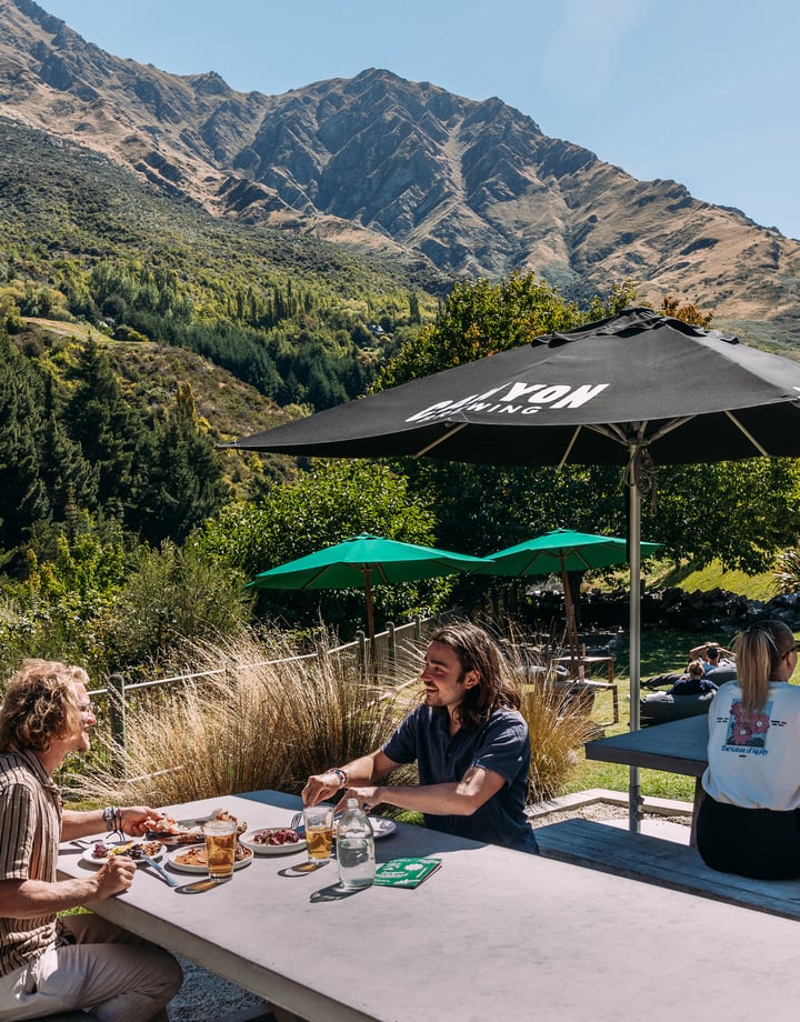 Four customers sitting at an outdoor table with nature scenery behind them.