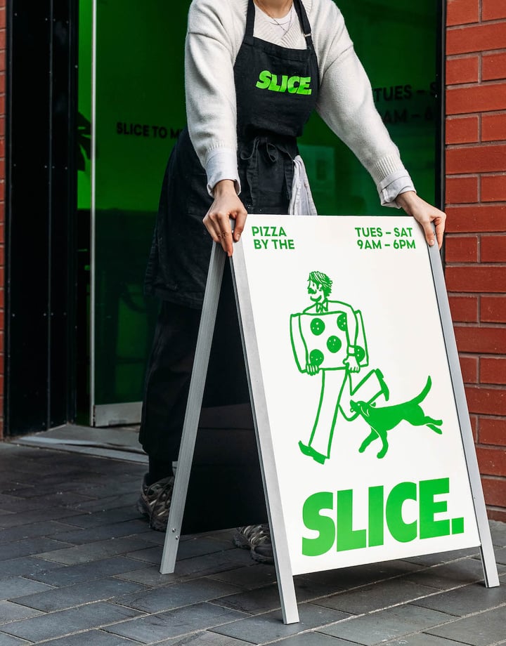 Someone putting Slice sandwich board sign outside shop