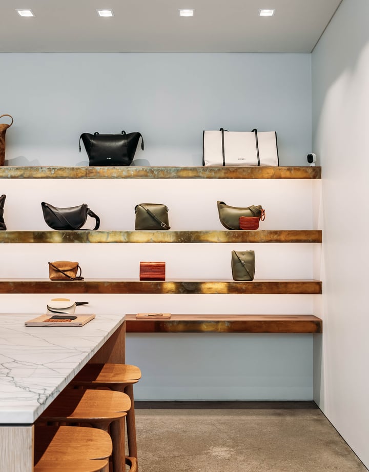 Leather bags on display on wooden floating shelves.
