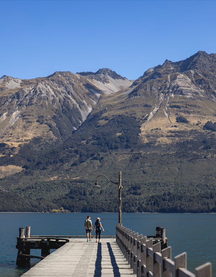 People standing on a wharf at a lake on a sunny day.