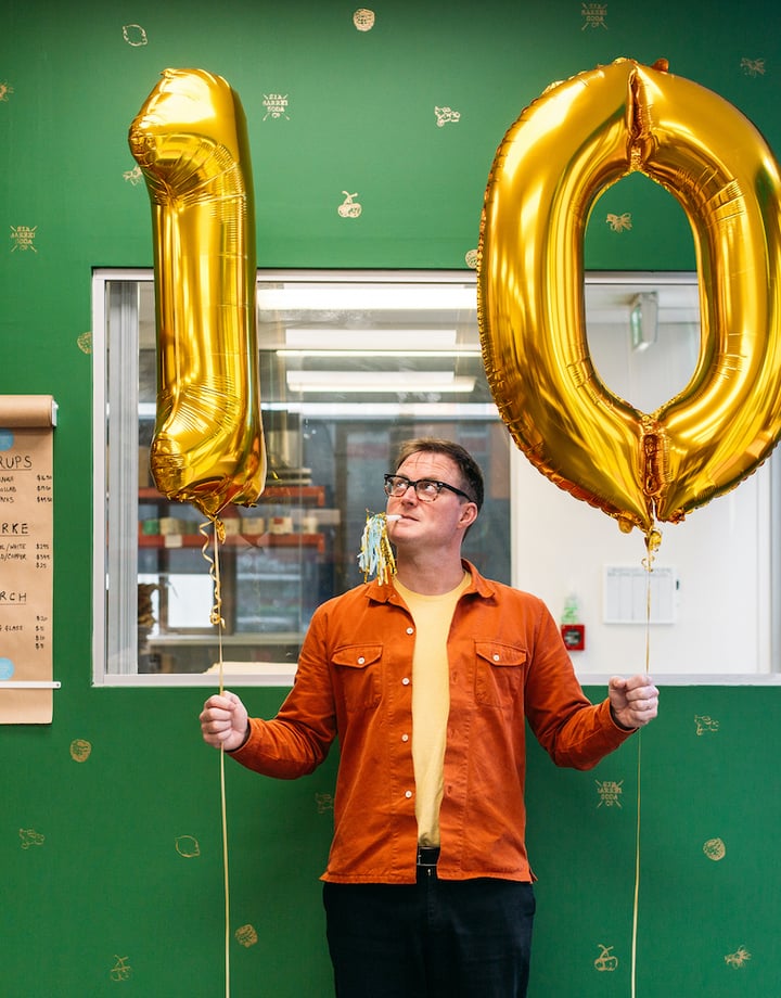 Joe Slatter holding two gold ballons with the numbers 1-0.