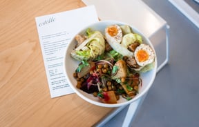 A plate of salads and boiled egg in a bowl on a table.