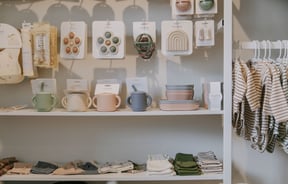 Baby bowls, cups and clothes displayed on shelves and racks in Lily and Langford Christchurch.