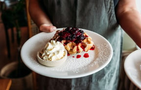 A close up of berries on waffles on a plate.