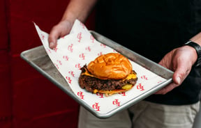Close up of a man holding a burger on a tray at Last Place Bar.