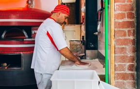 A staff member rolling out dough.