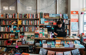 Male worker behind the counter of an independent bookstore in Petone Lower Hutt