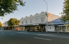 A view of old shops next to the road at dusk.