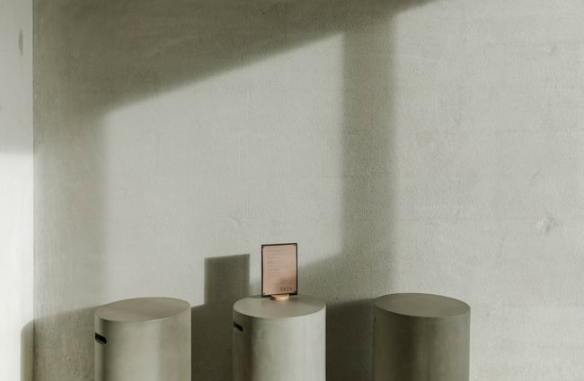 Three concrete stools up against a concrete wall.