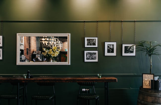 Dark green wall and hanging framed photos at Cellar Door in Christchurch.
