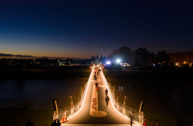 The He Ara Kotahi Bridge lite up with lights at night.
