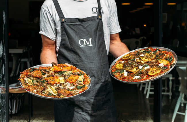 A chef holding two incredible looking pizzas!