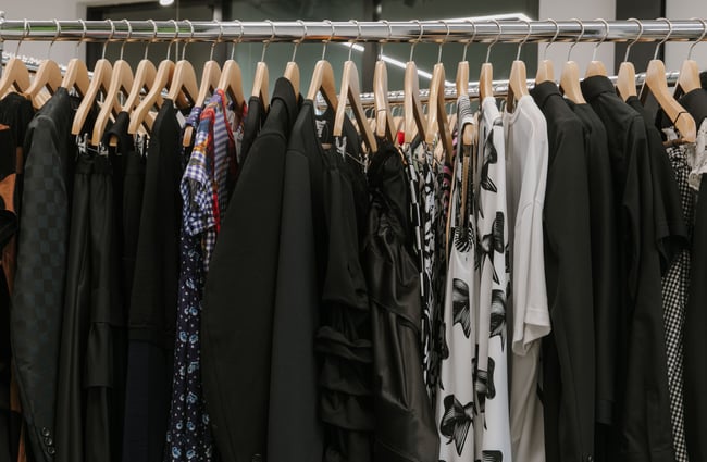 A close up of mostly black clothes on a rack.