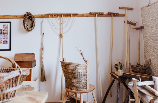 Rakes and items made of wood hanging on a white wall.
