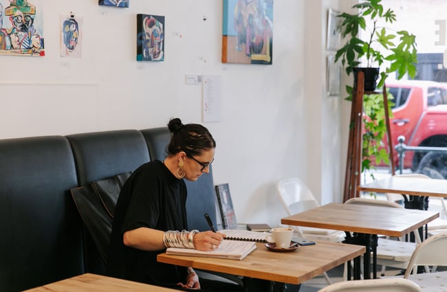 Woman having a coffee at a table whilst working.