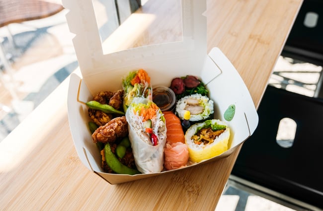 A white box holding fresh tasty looking sushi.