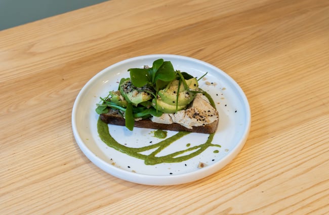 A plate of avocado on toast with a green drizzle.