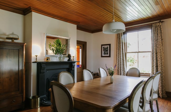 Dining room with table and original fireplace at French Bay House, Akaroa Canterbury.