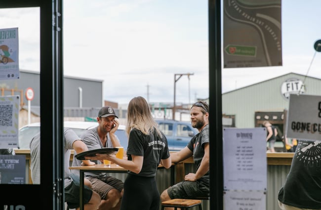 Waitress at a table of customers on the balcony at Ground Up Brewing, Wānaka.