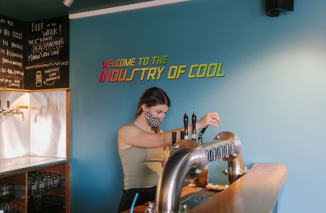 Woman pouring pint at Ground Up Brewing, Wānaka.