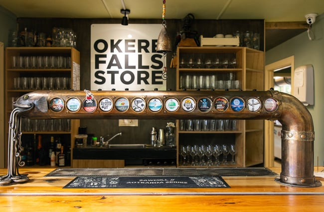The beer taps at Okere Falls Store, presented along the body of a metal fish scultpure.