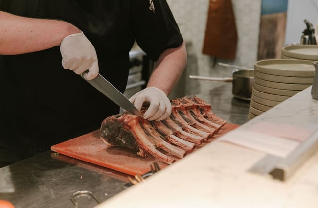 Chef preparing large cut of meat at Prohibition Smokehouse, Dunedin.