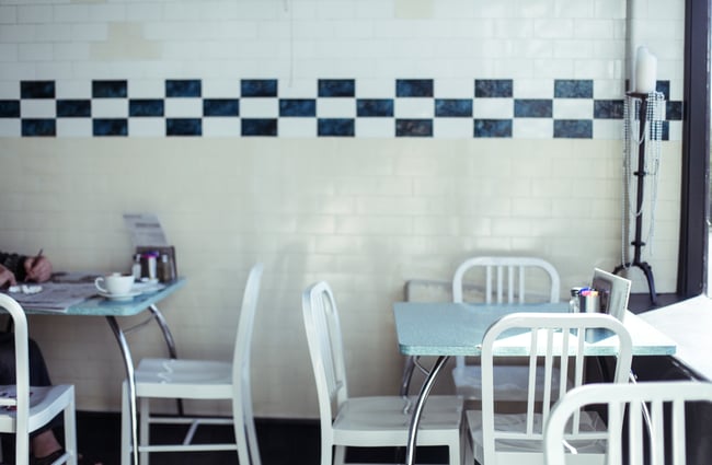 White tables and chairs by tiled wall.