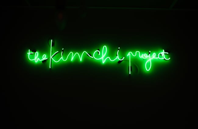 Green neon Kimchi Project sign.