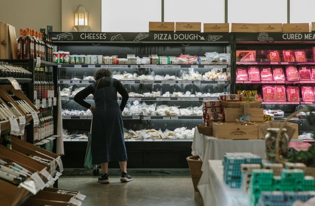 A woman looks at products in a fridge of cheese and pizza dough at The Mediterranean Food Company, Christchurch.