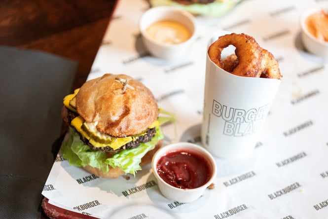 A burger and onion rings on a table.
