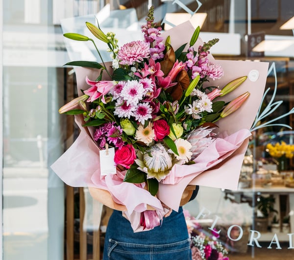 A woman holding a large bouquet of pink flowers.