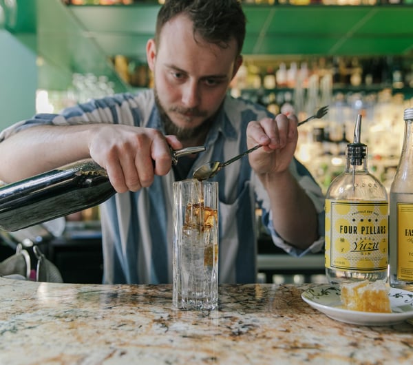 A bar man making a gin cocktail at the counter inside Gin Gin Christchurch.