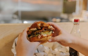 Close up of someone holding their burger about to take a bite.