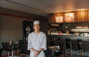 The Chef of Kinji Japanese restaurant standing in the middle of the restaurant smiling.
