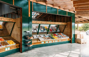 A fruit and vegetable display inside a large barn.