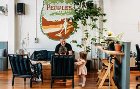 A man with child sitting on a couch at Peoples Coffee in Wellington, New Zealand.