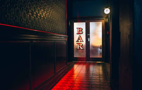 Bar sign in a dark hallway.