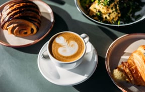 A milky coffee, pastries and savoury dish on the table at Scroggin, Wānaka.