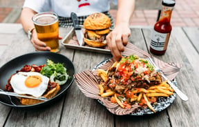 Loaded fries and other plates of food on an outdoor table.