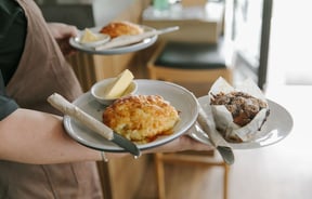 Person holding plates of muffins and cheese scones at Truffle café, Christchurch.