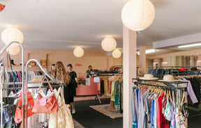 The busy and bright interior of a second hand clothing store.