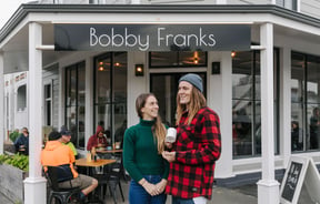 Kiera and Marc Shaw of Bobby Franks smiling at each other outside their Nelson cafe.