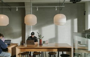 A man working on a laptop in a brightly lit cafe.