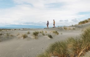 Two men walking along the beach on a sunny day.