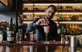 Barman placing a petal on a cocktail at Kismet.