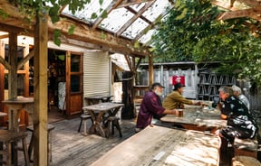 Men sitting around wooden tables outside Mussel Inn.