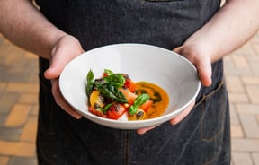 Hands holding a bowl of food made at Rascal in Christchurch.